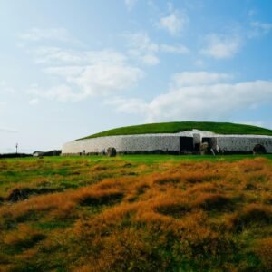 Ancient mound structure with green grass and blue sky.