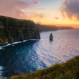 green and brown mountain beside body of water during sunset