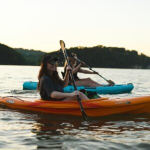 woman in blue shirt and blue denim jeans riding orange kayak on water during daytime
